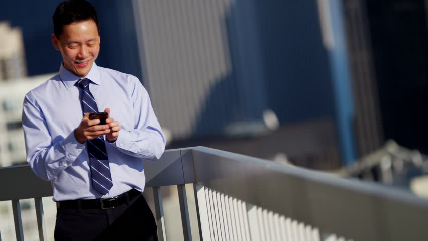 Confident young ethnic businessman using wireless app mobile technology on city rooftop skyscraper Chicago RED DRAGON