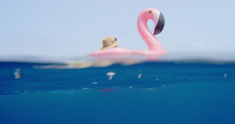 Woman lying on inflatable flamingo floating in middle of ocean girl relaxing in summer sunshine enjoying tropical vacation