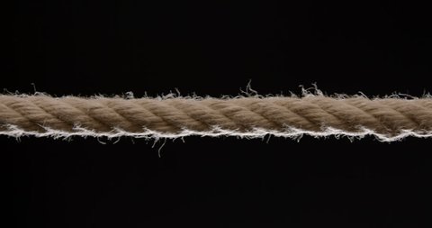 Close shot of rope being pulled across the frame against black