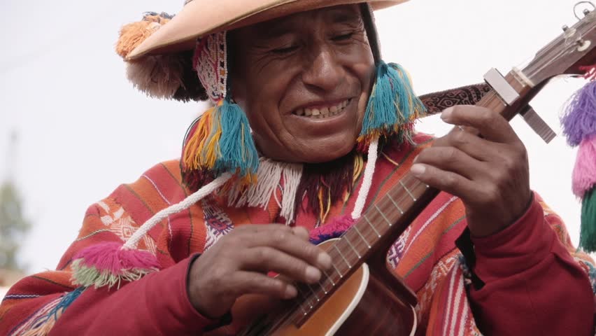 Native quechua man using a colorful handcrafted chullo and a highlander hat, singing with his guitar on the alleys of Cusco Royalty-Free Stock Footage #24242390