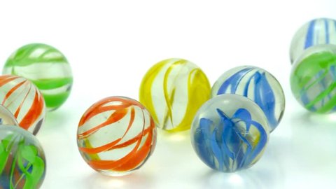 Rolling colorful glass marbles on white background