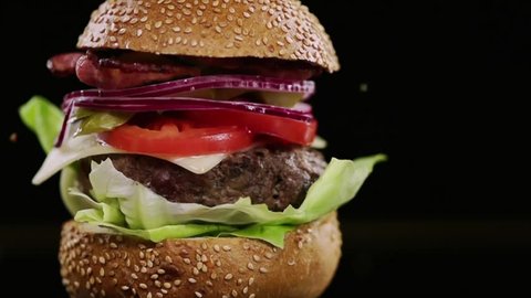 SLOW MOTION FOOD: a piece of bread falls on the finished burger and chips fly