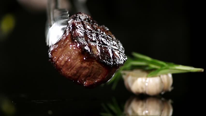 CLOSE UP FOOD: Cooking tongs put filet mignon on a black surface slow motion Royalty-Free Stock Footage #24250328