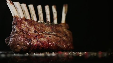 SLOW MOTION FOOD: spices fall on the rack of lamb close up