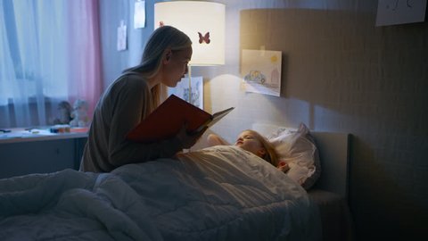 Young Loving Mother Reads Bedtime Stories to Her Little Beautiful Daughter who Goes to Sleep in Her Bed. Shot on RED EPIC-W 8K Helium Cinema Camera.