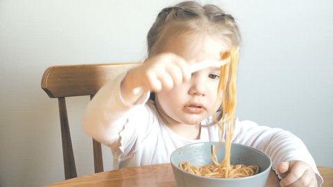 Cute little girl eating spaghetti