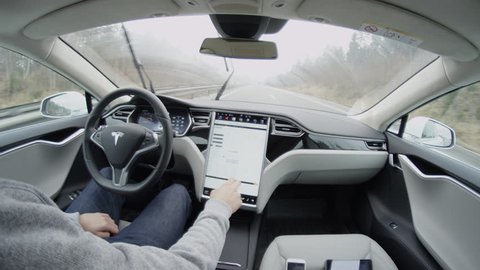 AUTONOMOUS TESLA CAR, FEBRUARY 2016:  Tesla autopilot self-driving in severe weather condition with no human intervention. Driver browsing the internet using touchscreen in futuristic autonomous car