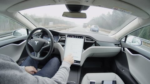 AUTONOMOUS TESLA CAR, FEBRUARY 2016:  Autonomous self-driving car Tesla Model S with enabled automated system driving in severe weather condition with no human intervention. Driver browsing internet