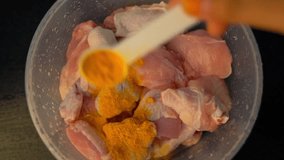 Pouring Turmeric into Fresh Parts of Chicken. Low Light Condition