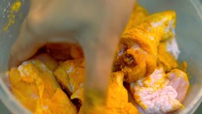 A Hand Mixing Turmeric Powder with Raw Chicken Parts. Focusing in The Middle