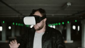 Young man standing in parking place wearing virtual reality glasses. Having fun with VR headset. 4K