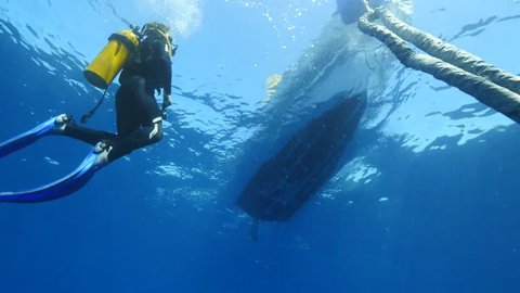diver ascending to the surface next to the boat by the line underwater
