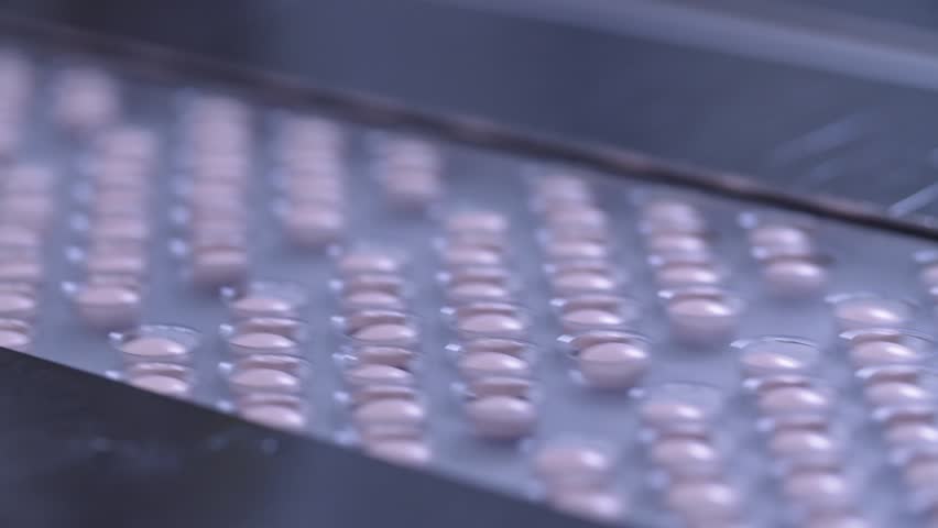 Automated packing at drug production. Closeup slow motion shot of an automated pill packaging machine.Tablets in Packages on a Conveyor. Pharmaceutical machinery for medicine production Pills. Royalty-Free Stock Footage #24266447