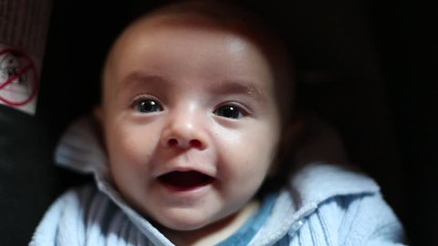 Small cute baby laughing and looking at the camera with a light blue sweater. Slow motion at 120 fps.