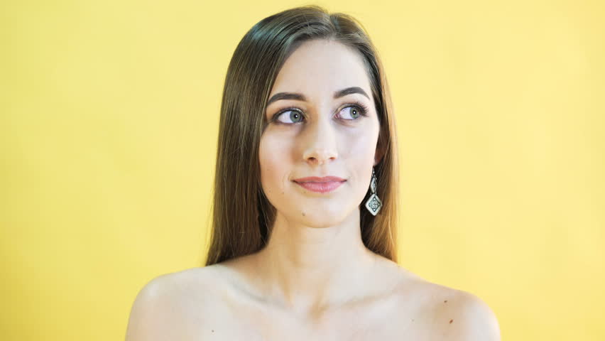 Portrait of thinking woman on yellow background. 4K