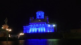 Zooming timelapse of people sightseeing blue colored, Helsinki Cathedral, at a dark new years evening night, in Helsinki, Finland.