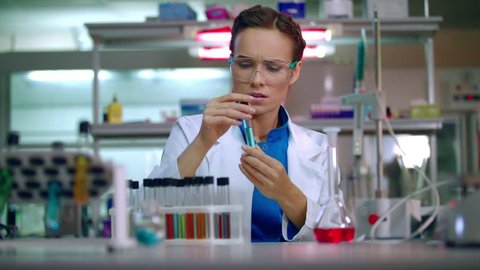 Female chemist in laboratory. Chemist analyzing chemical liquid in test tube. Woman chemist conducting chemical research in chemistry lab. Chemist woman working with chemical reagents in lab flask