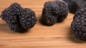 Tuber of black truffle rolls on the wooden table