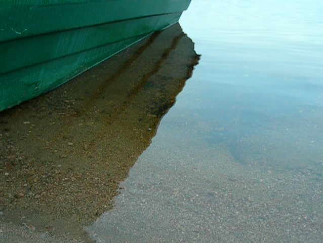 slow wave reflecting motor rowboat on a lake early in the morning