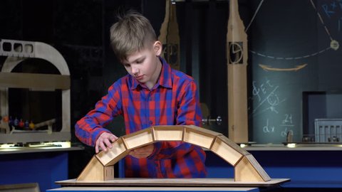 Boy 10 years building a bridge made of wooden blocks