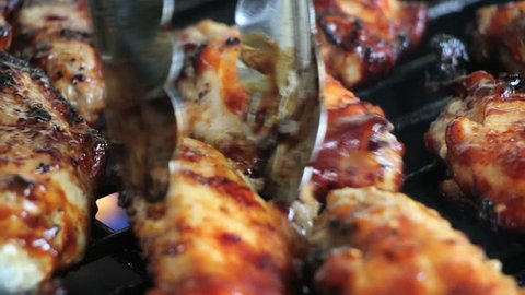 Grilling Chicken Drumsticks on BBQ & Man Flipping Them with Tongs