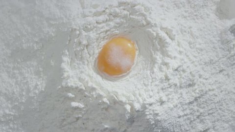 Slow motion of falling eggs into flour stock. Footage food. Egg dropping into flour, slow motion. Yolk Falls Into the Flour. Food Blog, Flour Products. Bakery products. Preparation of the dough