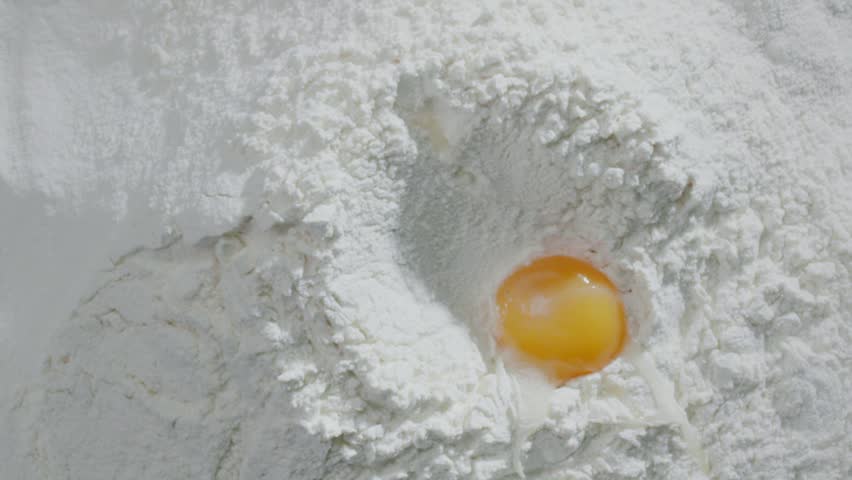 Slow motion of falling eggs into flour stock. Footage food. Egg dropping into flour, slow motion. Yolk Falls Into the Flour. Food Blog, Flour Products. Bakery products. Preparation of the dough