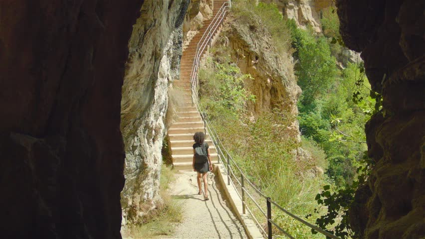 A woman in black dress climbs the staircase in the beautiful mountains