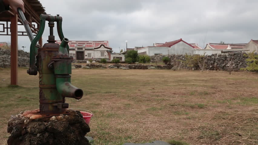 A woman is using a hand water pump in a village of Penghu, Taiwan.