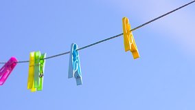 colored clothespins on clothesline, swinging wind against blue sky