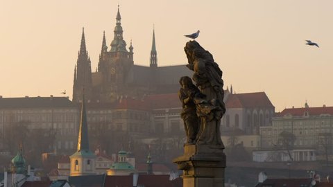 PRAGUE - FEB 10, 2017: Prague castle and a statue on the bridge at sunset in winter 