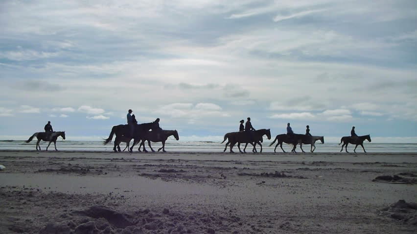 People enjoy horseback riding on sandy beach in Long Beach, Washington, real