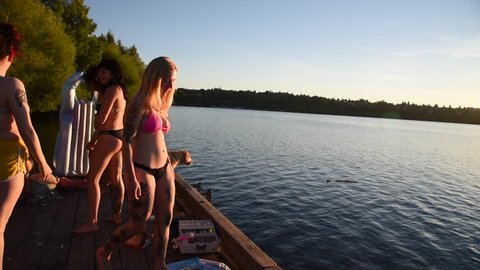 editorial footage illustrative Millennials enjoying an evening at Green lake Seattle Washington filmed July 20 2016 young women and men jumping into the water