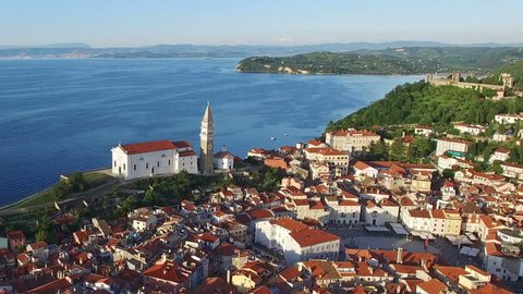 Flight over old city Piran in Slovenia, aerial panoramic view with old houses, St. George's Parish Church, Tartini Square, fortress and the sea. 