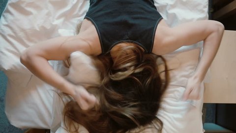 Tip view of angry woman falls face down on the bed. Girl beating her fist the pillows.