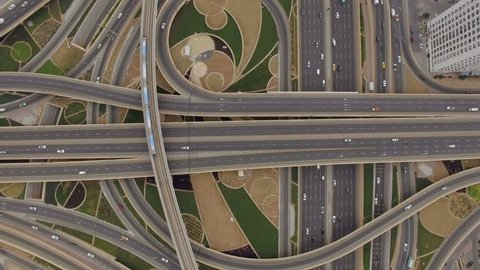 aerial view of road junction with moving cars and railway tracks on which the train rides. The concept of the urban form of Dubai, UAE