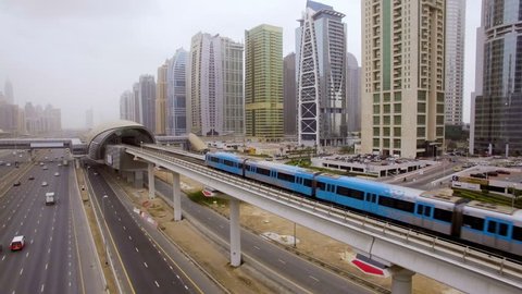 the train goes over the viaduct, along the highway among the skyscrapers in Dubai, UAE