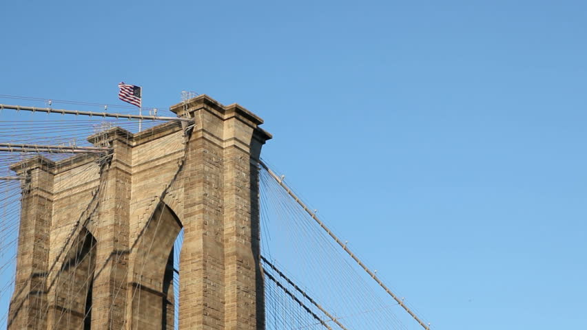 US Flag on top of the Brooklyn Bridge in the wind and sunshine on the brick