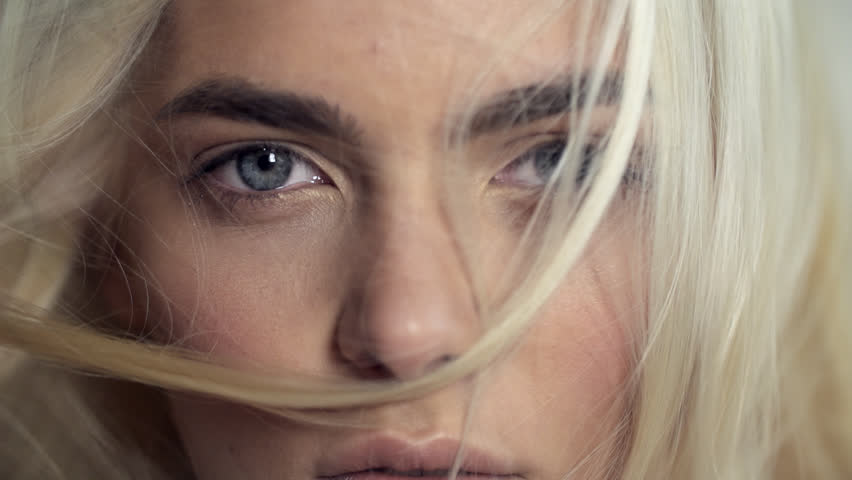 Close-up face of a beautiful blonde with blue eyes in Slow Motion