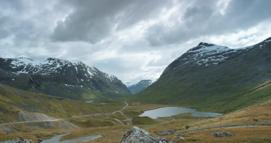 Woman with arms raised on top of mountain looking at view of glacial valley Hiker Girl wearing green jacket lifting arm up celebrating scenic landscape enjoying vacation travel adventure nature Norway