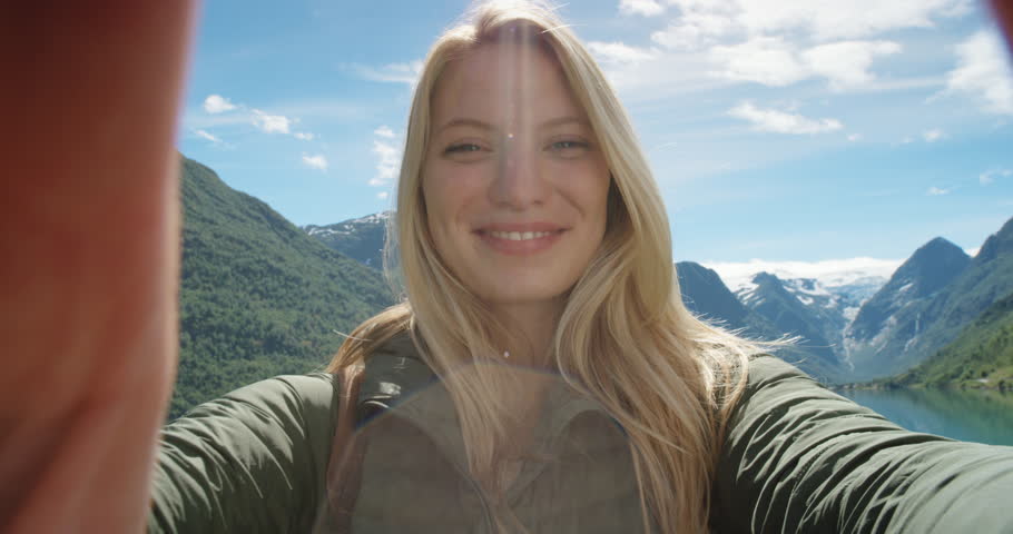 Beautiful woman having video chat using smartphone outdoors sharing travel adventure  friends showing lake and glacier Girl filming selfie video photo for social media  Norway vacation slow motion Royalty-Free Stock Footage #24370124