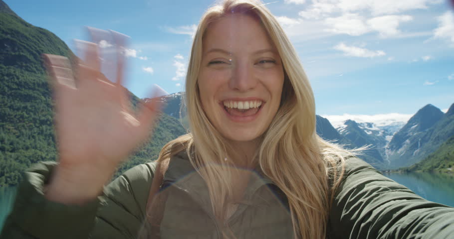 Beautiful woman having video chat using smartphone outdoors sharing travel adventure  friends showing lake and glacier Girl filming selfie video photo for social media  Norway vacation slow motion