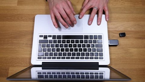 Typing on a modern laptop computer and inserting a USB stick on a wooden desk top view