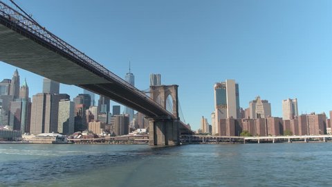 LOW ANGLE VIEW, CLOSE UP: Amazing sightseeing boat cruise on the East River, traveling past famous New York City skyscrapers toward iconic Brooklyn Bridge and apartments in Little Germany neighborhood