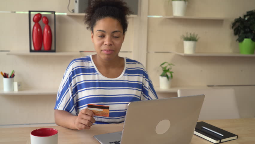 Mixed race woman shopping online. satisfied customer buy remote using internet and laptop holding credit card.