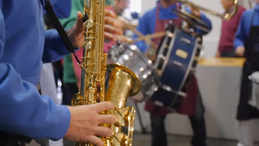 Musician passionately playing on saxophone in background with drummers
