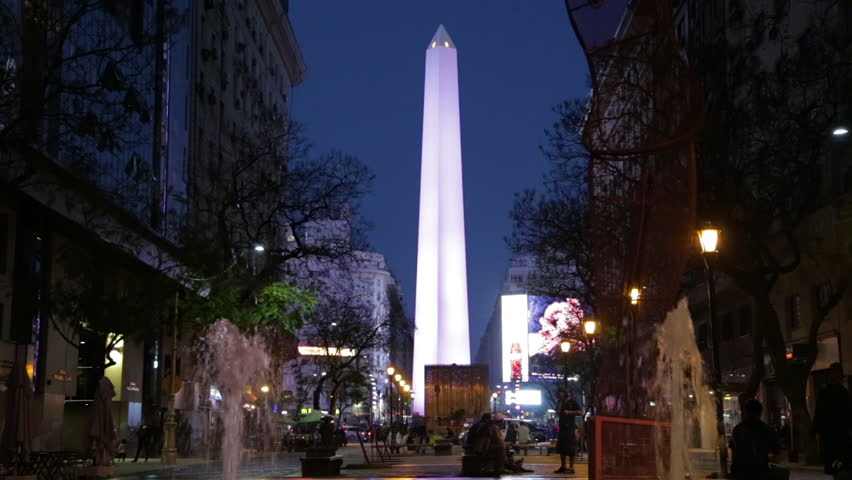 Famous Buenos Aires Obelisk light up at night. Fountains, people, and buildings in the foreground