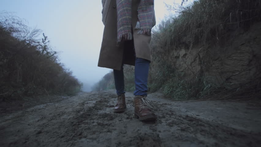 Legs of a young girl go on a dirt road in the woods