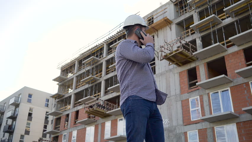 Construction manager talking by smartphone at building place. Slider shot. Royalty-Free Stock Footage #24392570