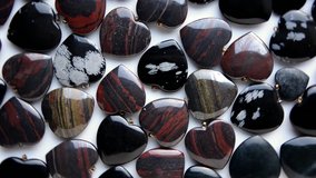 Snowflake obsidian red and iron tiger eye semiprecious stone hearts are rotating on white background top view - Powered by Shutterstock - Get 15% off with code: PIKWIZARD15